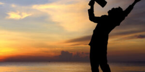 Person shouting into megaphone by a beach.